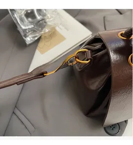 Close-up of brown polished leather bag texture with vintage gold metal hardware buckle