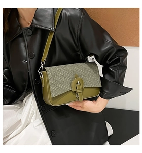 Detail of green quilted crossbody bag with straw woven flap and vintage metal buckle