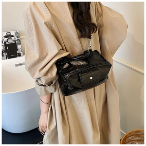 Detail of glossy black patent leather handbag with pleated texture and magnetic flap pocket
