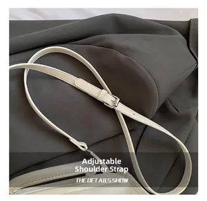 Close-up of adjustable cream leather shoulder strap with silver buckle detail on a tote bag