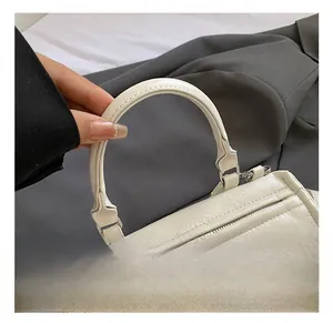 Close-up of white leather tote bag handle with silver hardware and lychee grain texture