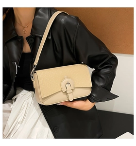 Détail d'un sac bandoulière beige matelassé avec boucle fer à cheval porté par un mannequin