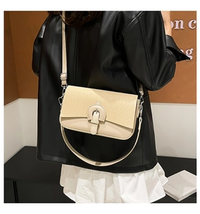 Detail of beige shoulder bag with textured flap, horseshoe buckle, and thin strap