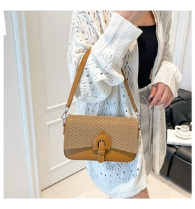 Detail of a beige woven and light brown leather shoulder bag on a model in a minimal room