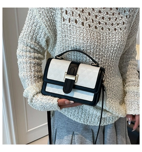 Detail of b&w contrast square bag with geometric embossing and gold clasp closure