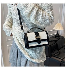 Detail of black and white crossbody bag with geometric embossing and gold clasp
