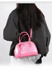 Pink snakeskin embossed shell bag with glossy finish and gold hardware on grey suit