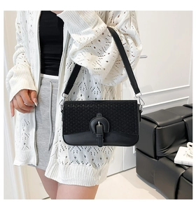 Détail d'un sac porté épaule noir avec texture tissée et empiècements en cuir élégants