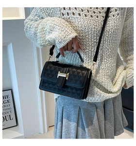 Detail of black quilted leather handbag with gold H buckle and triangular stitching pattern
