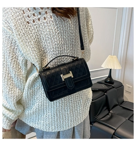 Detailed view of black quilted leather crossbody bag with golden H clasp hardware