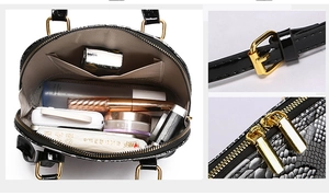 Detail view of black snakeskin embossed shell bag showing spacious interior and gold hardware