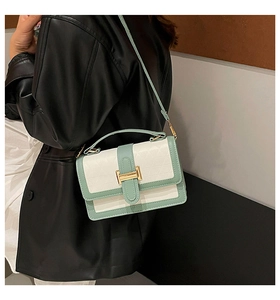 Detail of color-block crossbody bag with geometric embossing and gold metal clasp closure