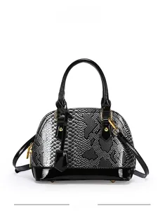 Detail of snakeskin pattern shell bag with black patent leather and gold hardware
