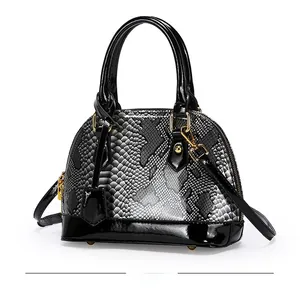 Detail of snake skin pattern handbag with shiny patent leather trim and gold hardware