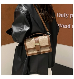 Detail of crossbody bag featuring gold H-shaped lock with geometric print and brown leather