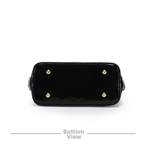 Detail view of the black patent leather shell bag bottom with gold metal protective studs