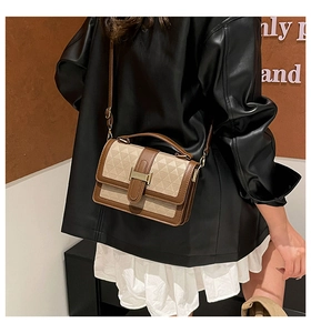 Close-up of contrast color handbag with geometric texture and gold H-buckle detail