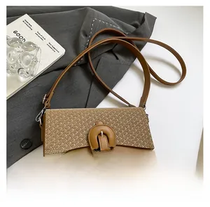 Detail of a brown leather crossbody bag with cream woven fabric and horseshoe buckle closure