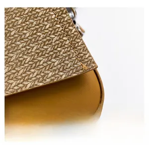 Macro detail of textured straw weaving and smooth matte leather stitching on the shoulder bag