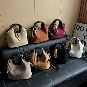 Quilted bucket bag with beaded charm in seven vintage colors on a stylish leather bench