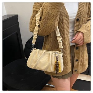 Detail of cream pleated shoulder bag with wooden bead charm on a knit cardigan outfit