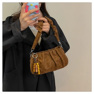 Detail of leopard print pleated shoulder bag with wood bead charm and ruched handle