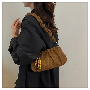 Close-up of leopard print shoulder bag featuring vintage beads and pleated strap detail