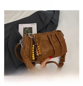 Detail of a brown suede pleated shoulder bag with colorful wooden bead charm and silver hooks