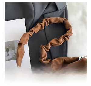 Close-up of caramel brown ruched handbag with elegant cloud handle and metal clasp