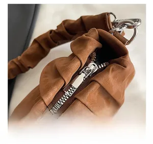 Detailed close-up of the smooth silver zipper and pleated texture of the brown handbag