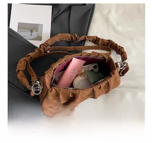 Internal storage detail of caramel pleated cloud bag with phone and cosmetics