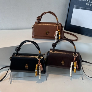 Vintage retro women handbag in brown and black leather with gold clasp and tassel charm