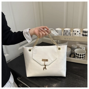 Detail of white leather shoulder bag featuring gold chain and deer pendant charm