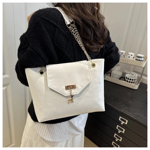 Detailed side view of white faux leather tote with gold deer buckle and chain strap