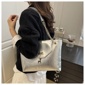 Detail of silver metallic tote bag with stag charm and gold chain shoulder strap