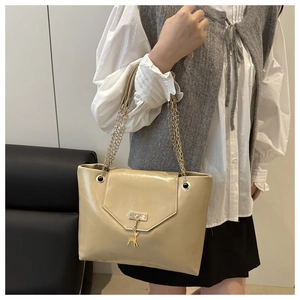 Detail of beige glossy leather handbag with golden chain strap and deer pendant charm