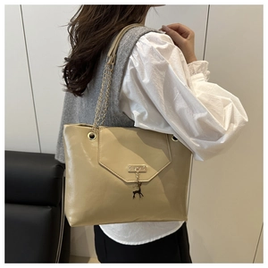 Detail of beige tote bag with golden chain strap and signature deer metal pendant