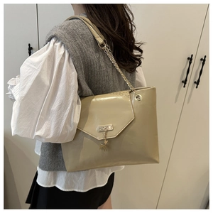 Detail of khaki tote bag featuring an envelope flap with a deer pendant and chain strap
