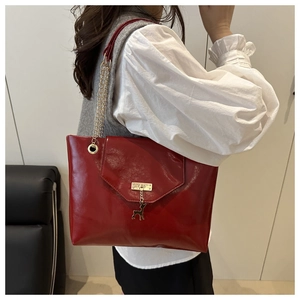 Detail of red patent leather tote bag with gold deer pendant and chain shoulder strap
