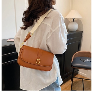 Detailed close-up of a brown rectangle shoulder bag with gold square buckle and strap
