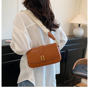 Brown leather crossbody bag detail featuring golden square buckle and wide fabric strap
