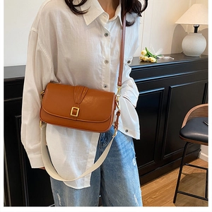 Detail view of caramel faux leather bag with wide canvas strap and gold buckle