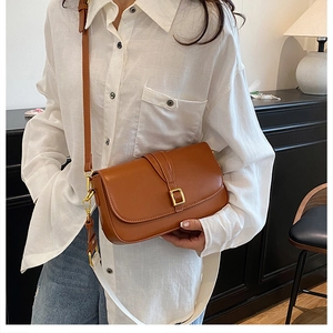 Detail view of brown leather crossbody bag with gold buckle and interchangeable straps