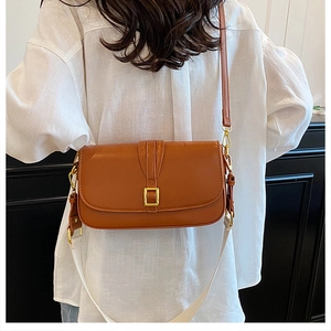 Close-up of caramel leather crossbody bag featuring gold buckle and white wide strap