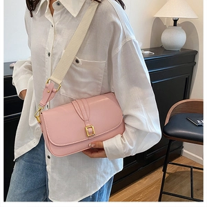 Pink faux leather crossbody bag detail with wide fabric strap and golden metal buckle
