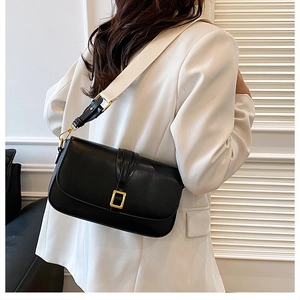 Detail of black leather square crossbody bag with beige wide strap and gold buckle