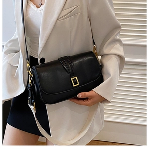 Detail of black crossbody bag featuring gold hardware and wide decorative shoulder strap