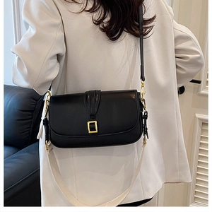 Detailed view of black leather crossbody bag with gold buckle and dual strap options