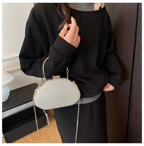 Silver glitter evening bag with gold metal handle and chain worn by a model