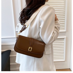 Brown leather crossbody bag detail with gold metal buckle and wide woven shoulder strap